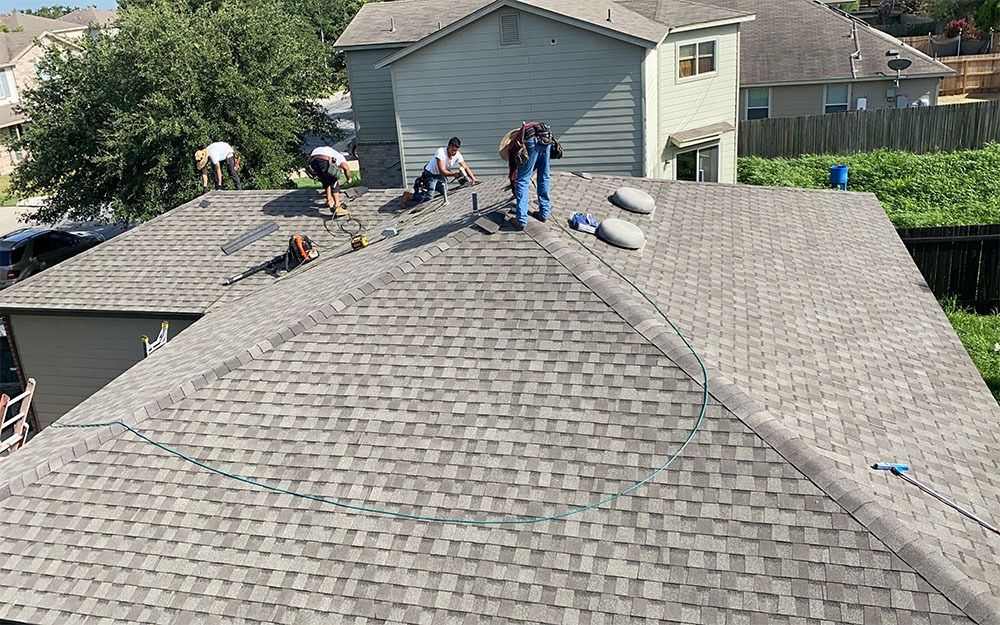 A group of people are working on the roof of a house in San Antonio, TX.