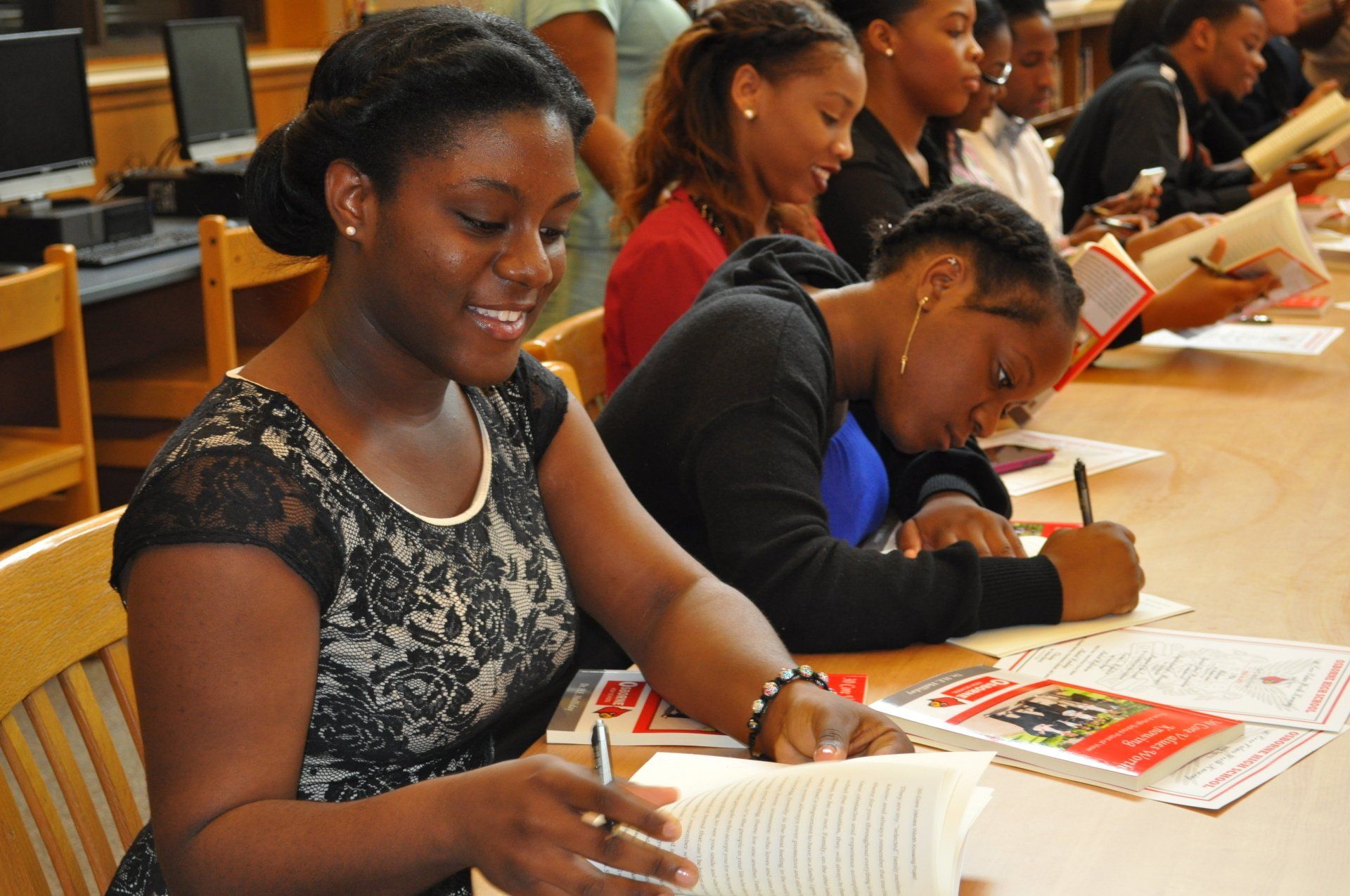 A group of people are sitting at a table reading books
