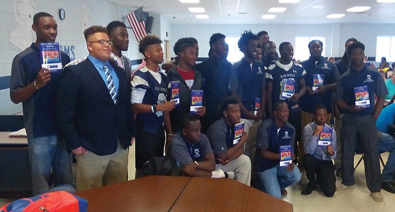 A group of young men are posing for a picture in a room holding books