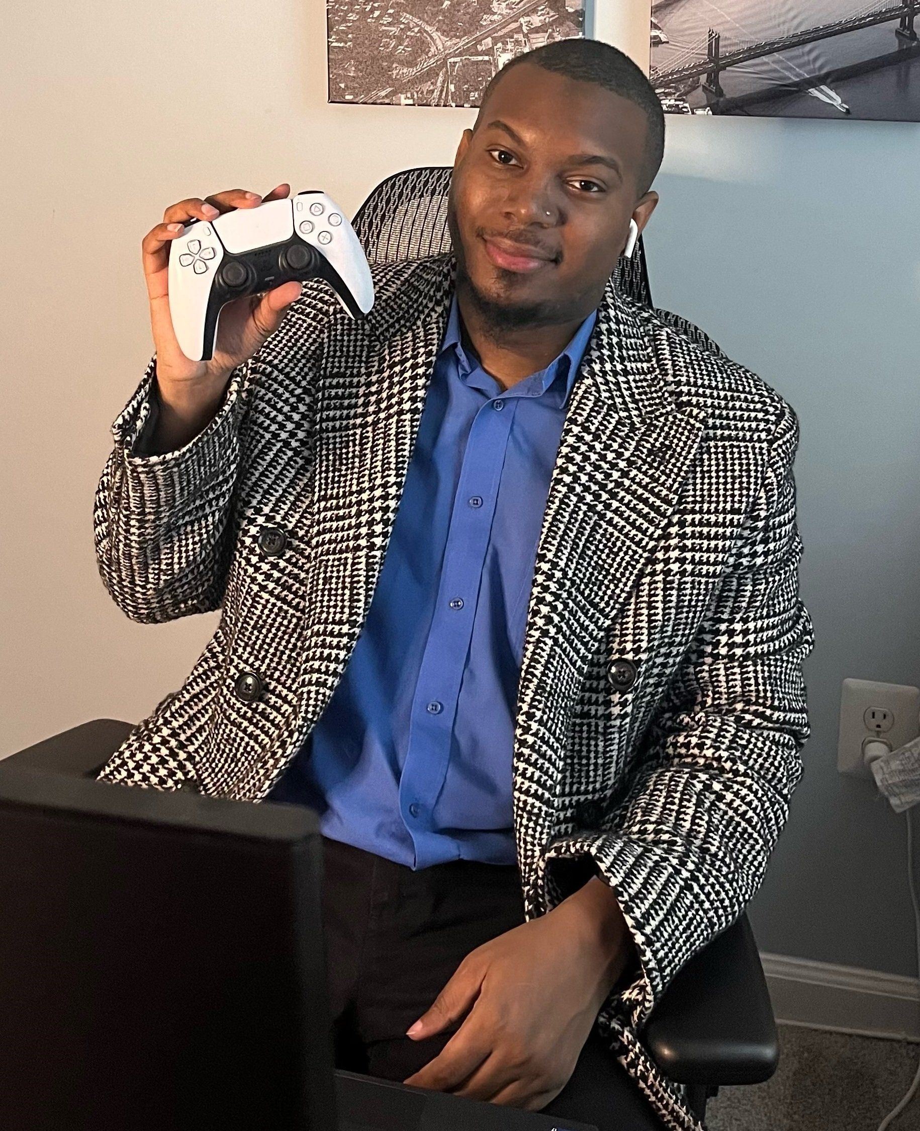 A man in a suit is holding a video game controller while sitting in front of a computer.