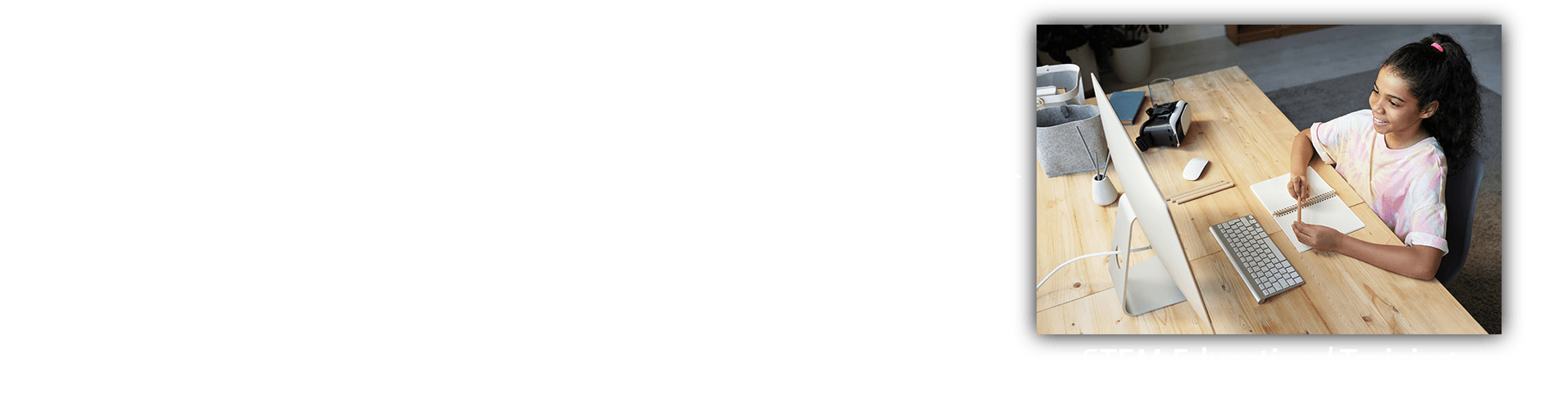 A woman is sitting at a wooden desk using a laptop computer.