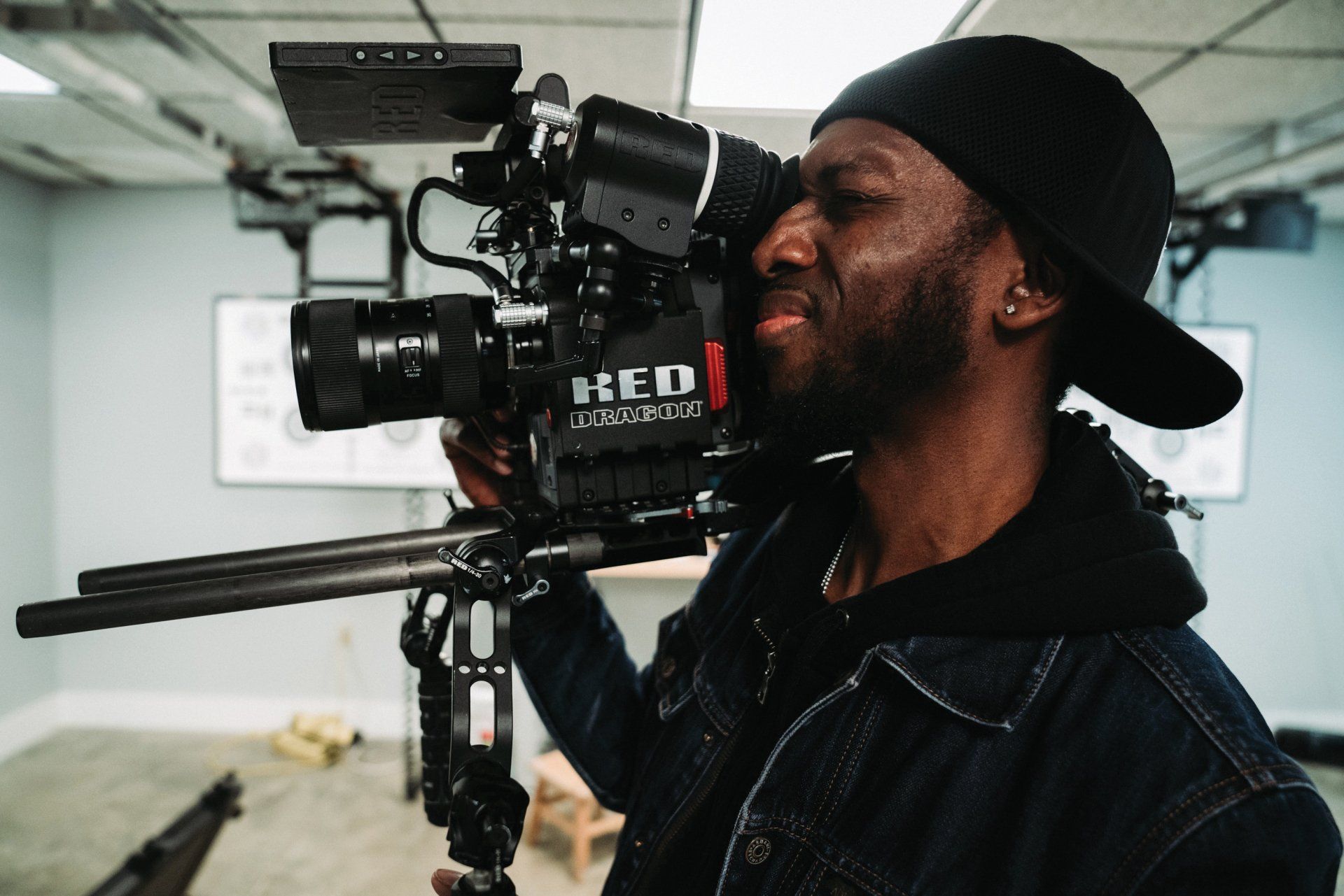 A man is holding a red camera in a room.