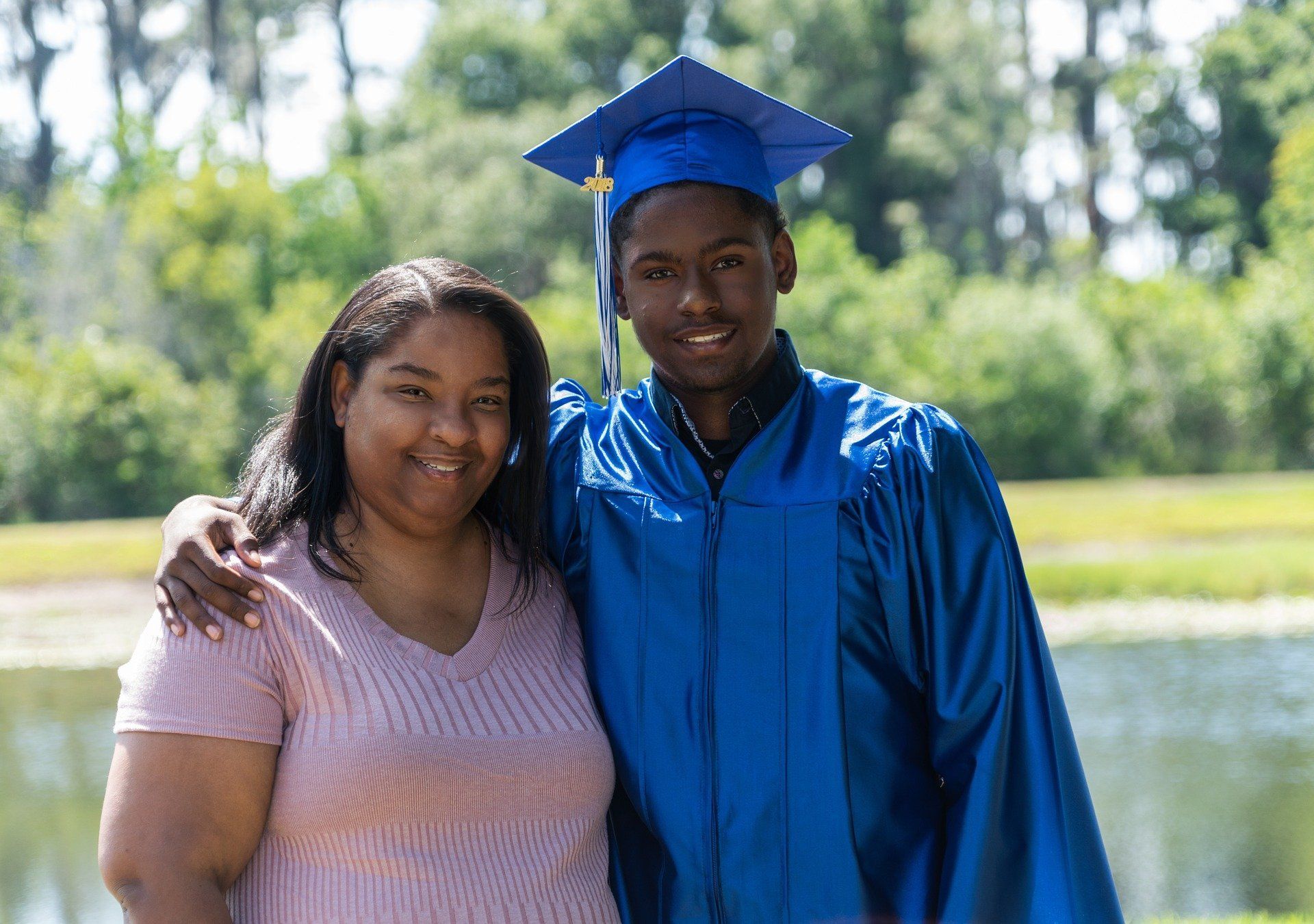 A woman is standing next to a man in a graduation cap and gown.