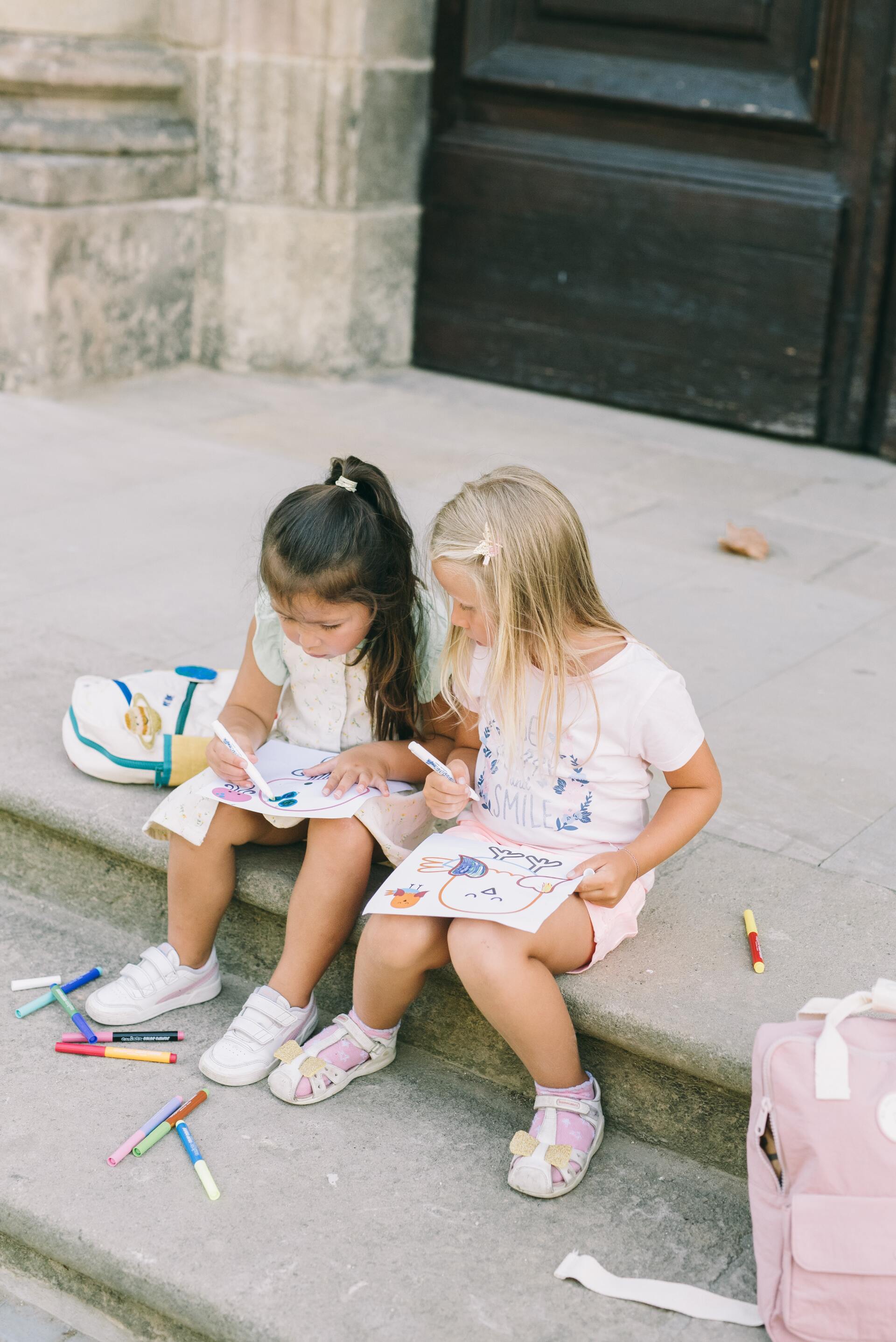 Two little girls are sitting on the steps of a building.