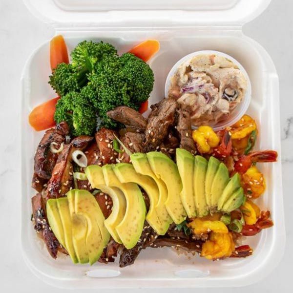 A styrofoam container filled with a variety of vegetables and meat.