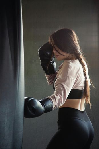 Woman in boxing gloves punches a heavy bag in a gym.
