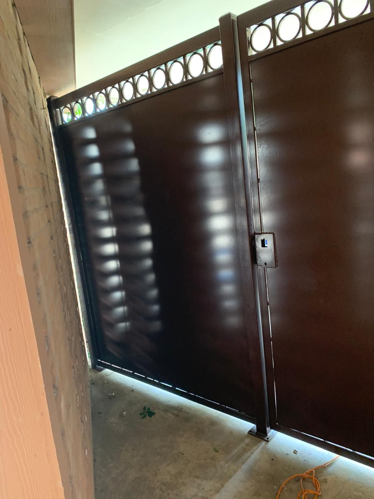 Dark brown metal gate with circular design at the top. A lock is visible.