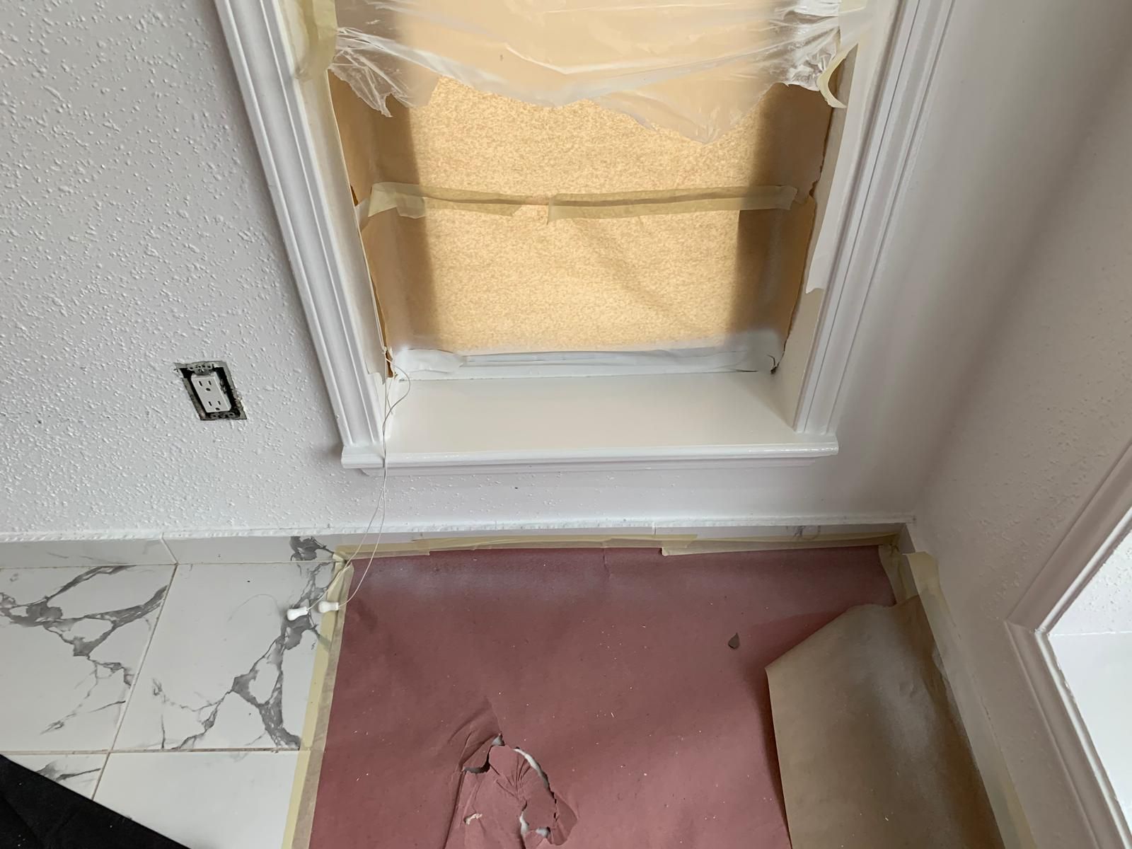 Ceiling window frame with plastic, pink flooring, and white marble tile.