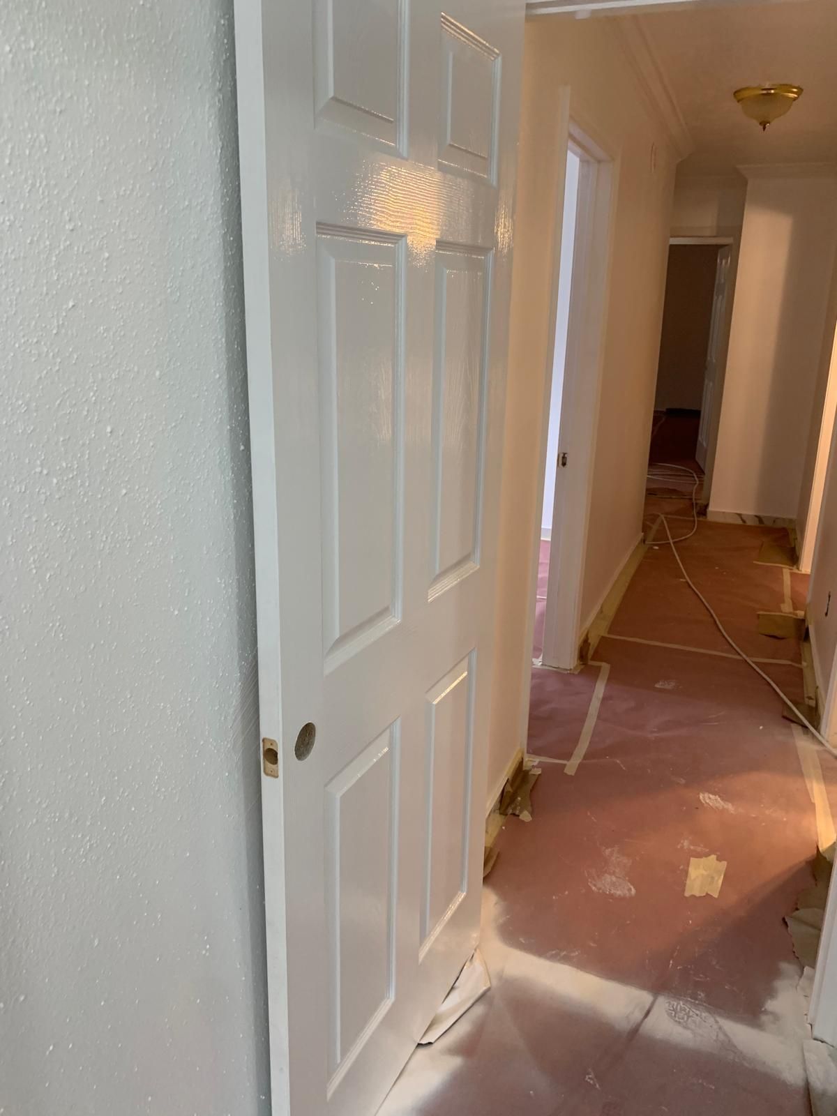 White six-panel door in a hallway with protective paper on the floor.