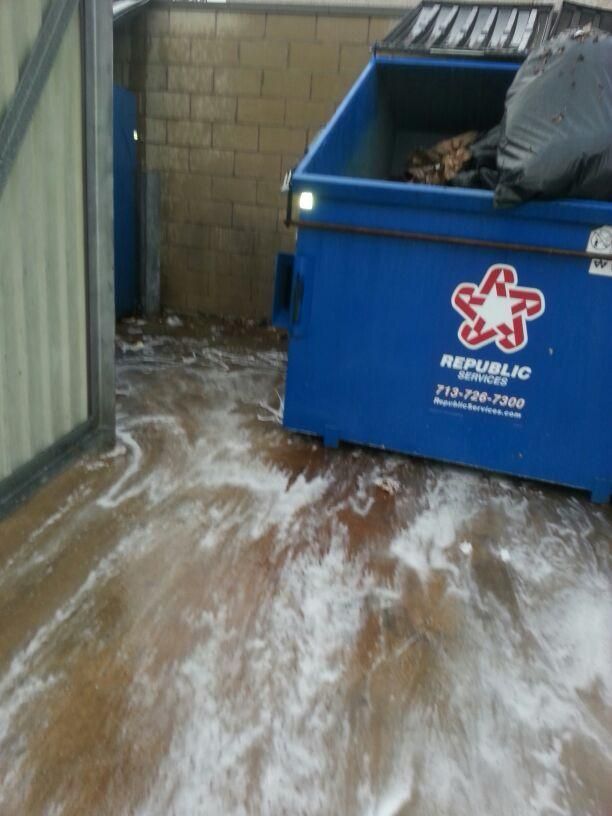 Blue Republic Services dumpster with trash next to a wall and a dirty floor.