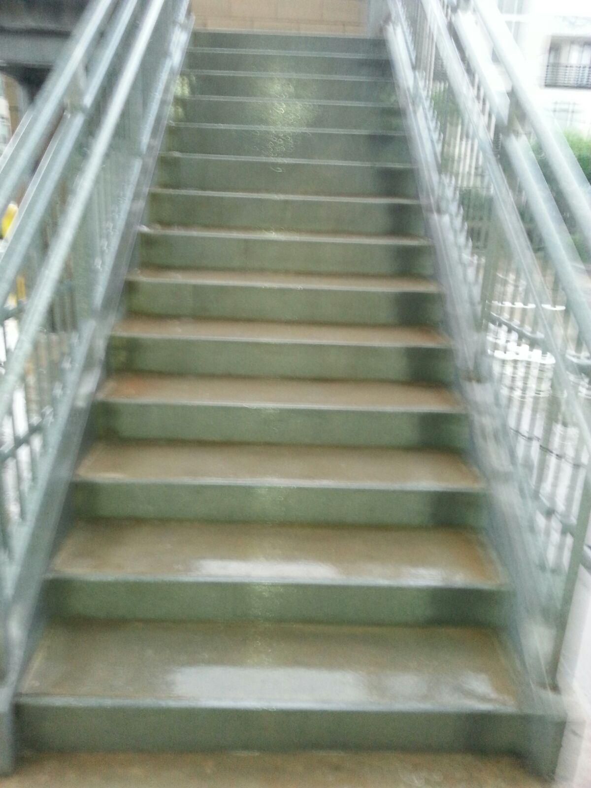 Gray metal stairs with railings, leading upwards.