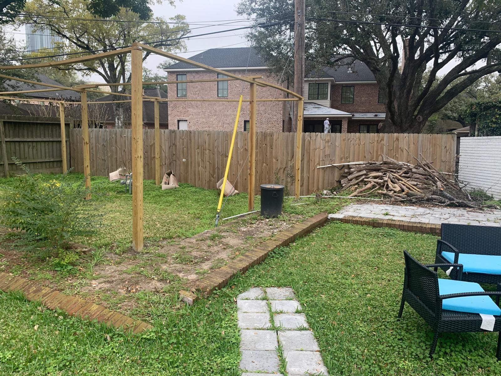 A backyard with a wooden pergola, wooden fence, and patio furniture.
