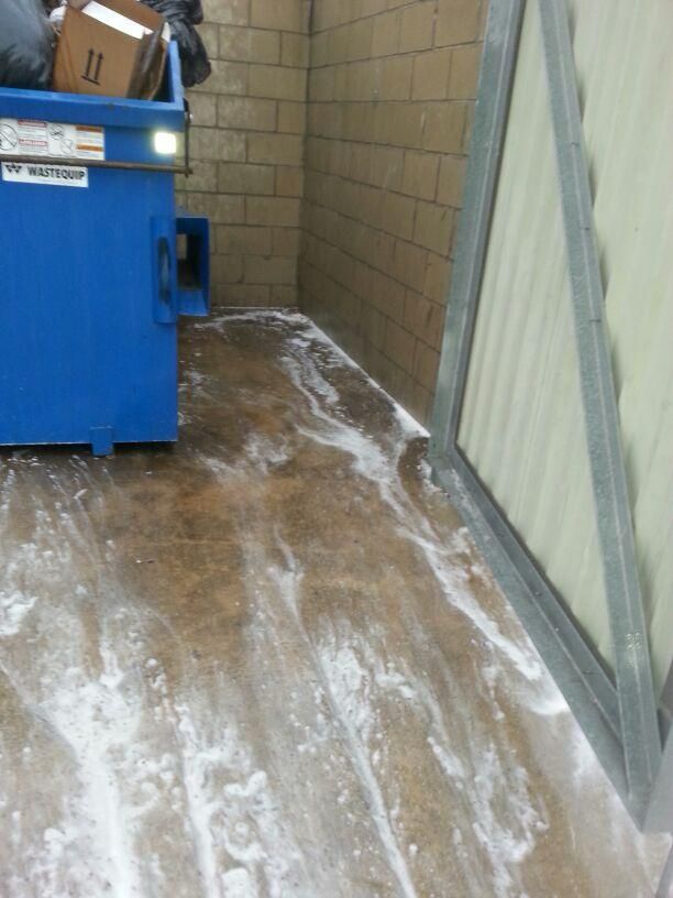 Blue dumpster and white foam on concrete floor in enclosed space.