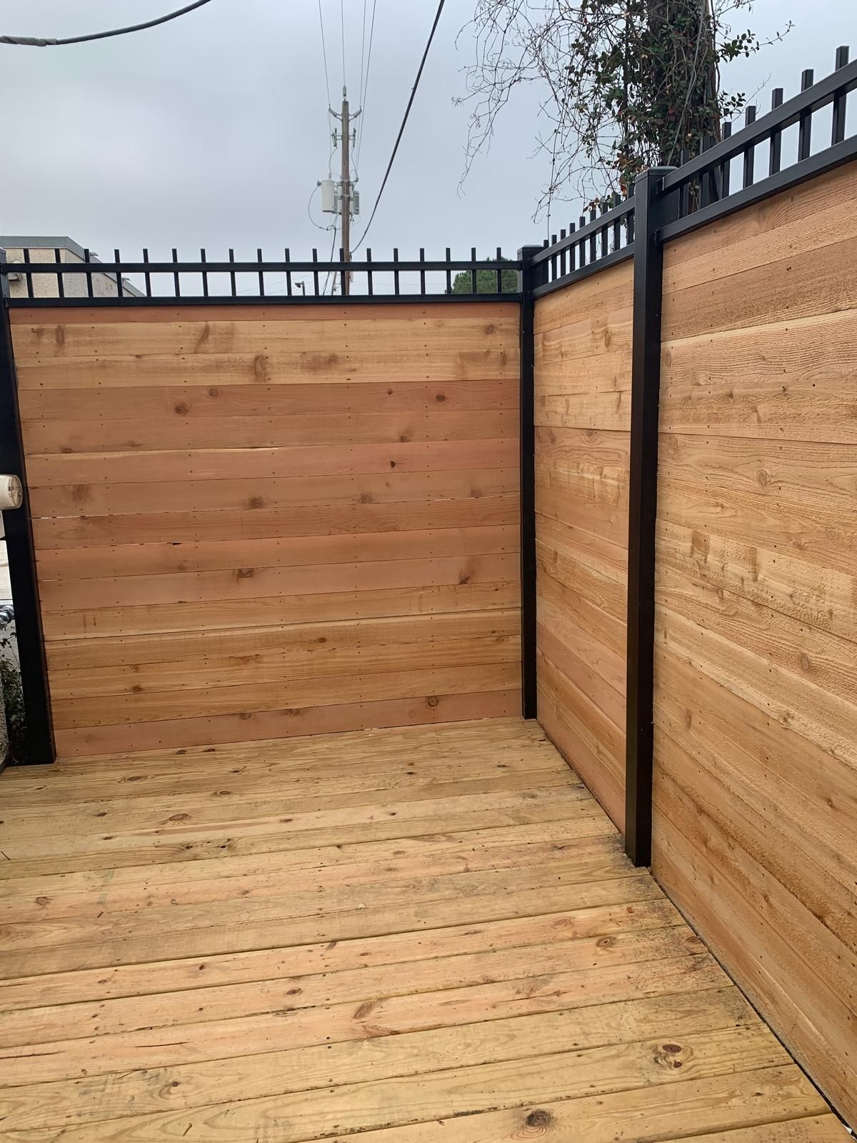 Wooden deck and privacy fence with black metal accents.