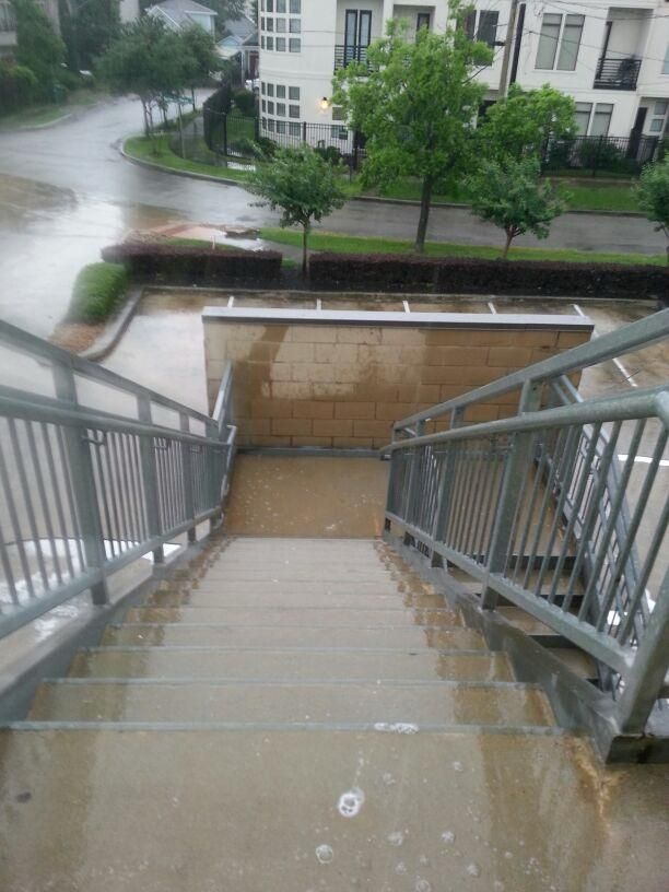 Rainy outdoor stairs with metal railings, leading downward to a wet concrete landing.