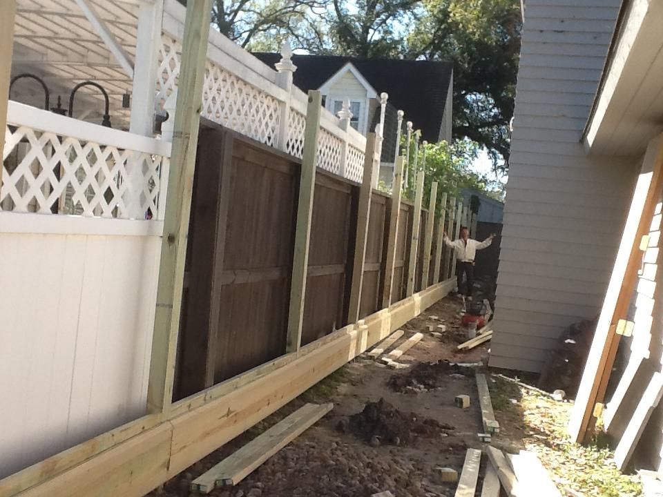 Fence under construction; wooden posts and boards added to existing fence. Person in background.