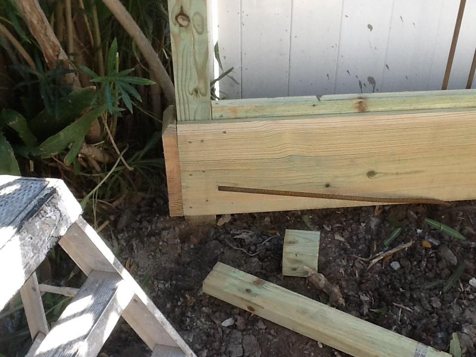 Wooden fence construction with green and white wood, and a small ladder.