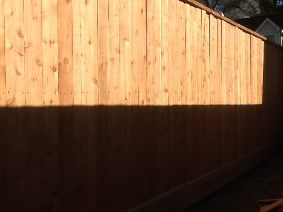 Wooden fence with a horizontal shadow, sunlight, and dark wood.