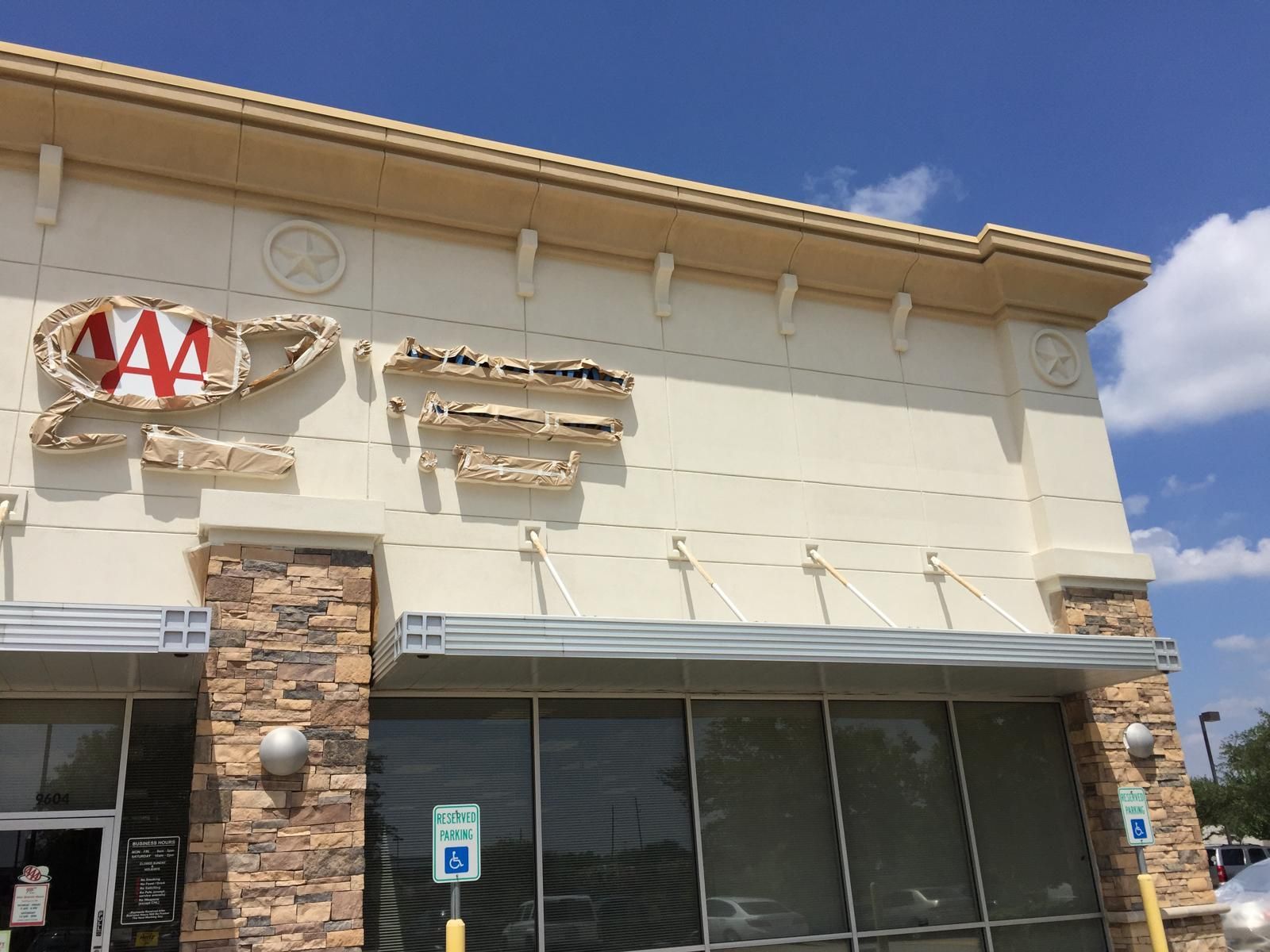 AAA building with damaged signage, blue sky background.