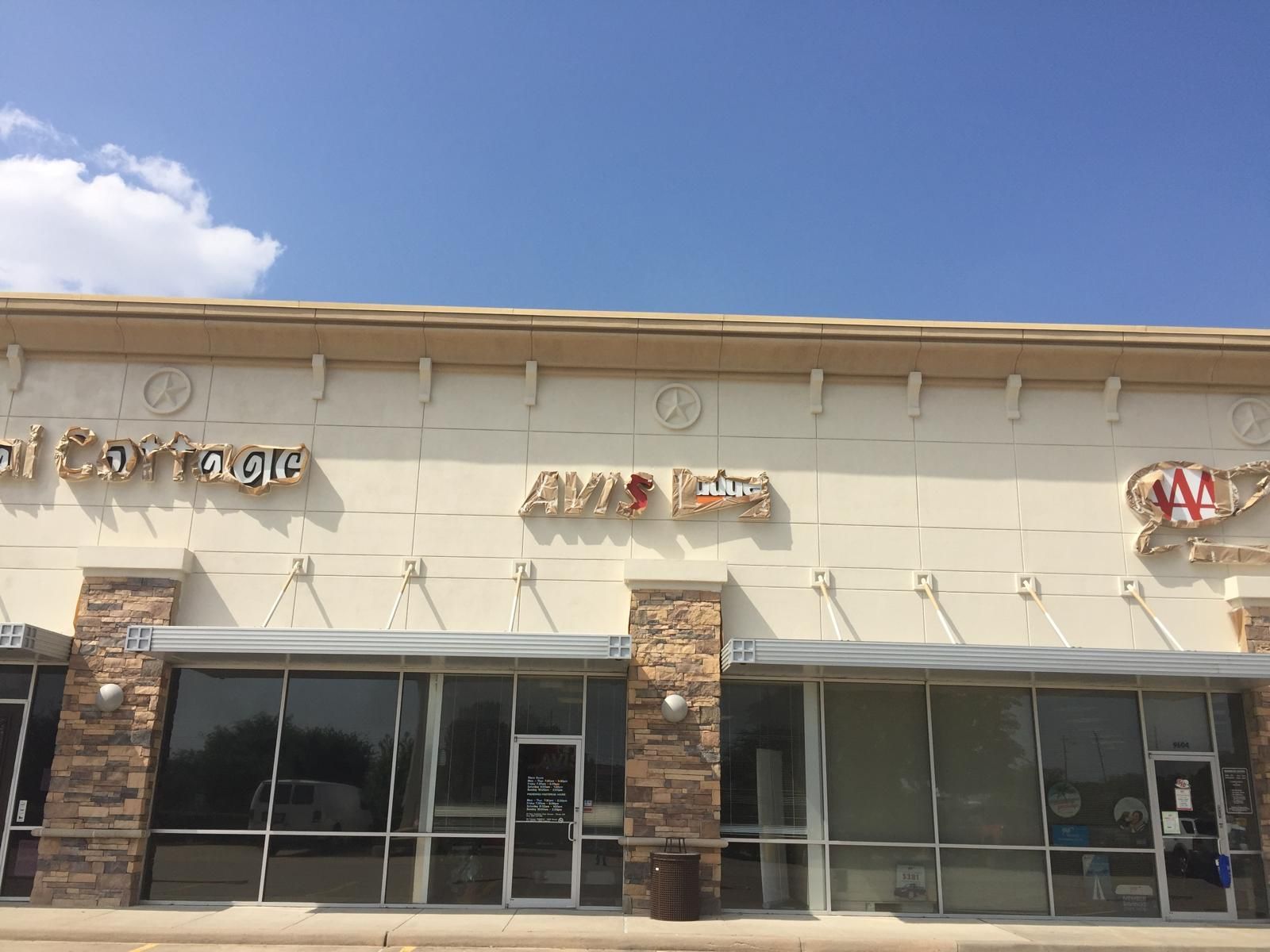 Exterior of a strip mall with storefronts, including businesses named 