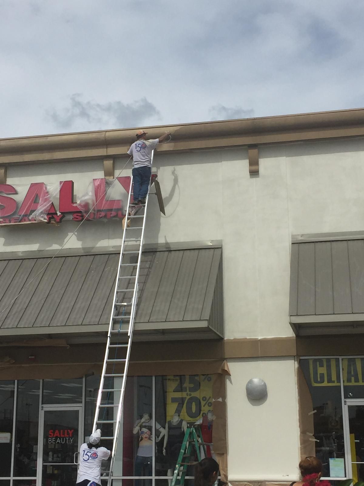 People on ladders painting 