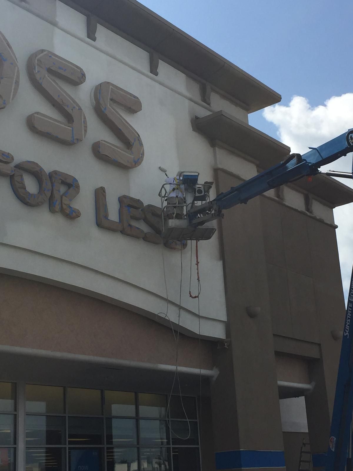 A Genie lift is near a Ross store sign, working on it.