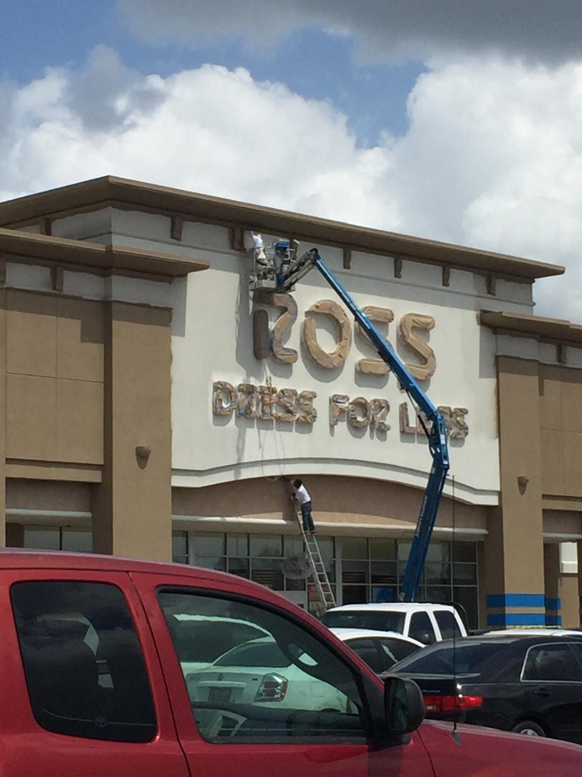 Workers on lifts installing signage for Ross Dress for Less at a shopping center.