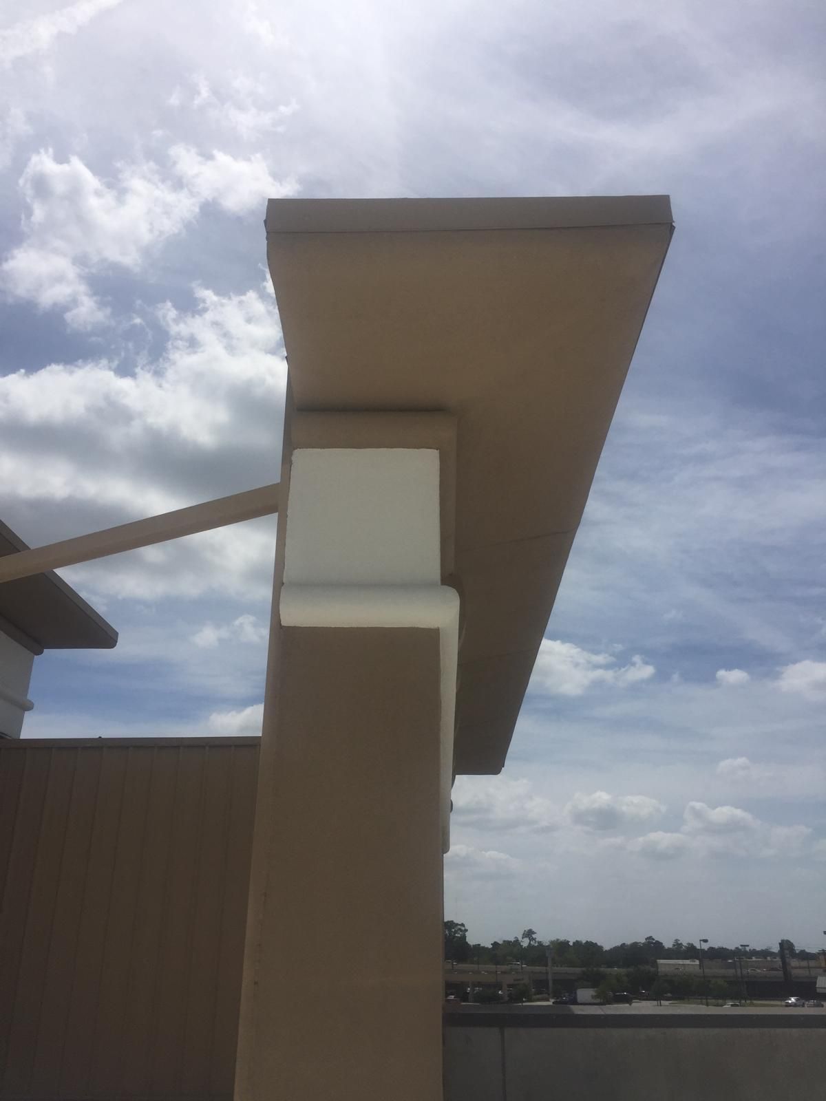 Beige overhang supported by a beige column with a white section against a partly cloudy sky.