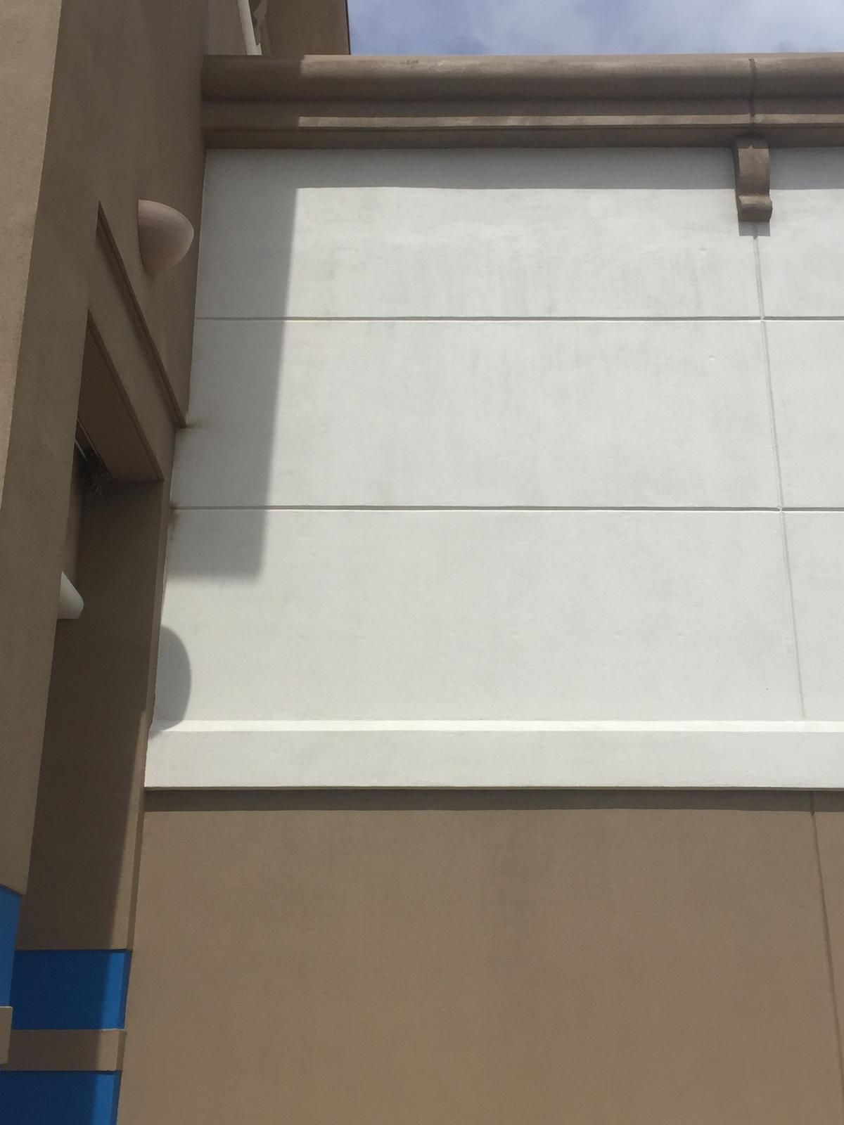 Tan and white building exterior; blue accent stripe; sunny day.