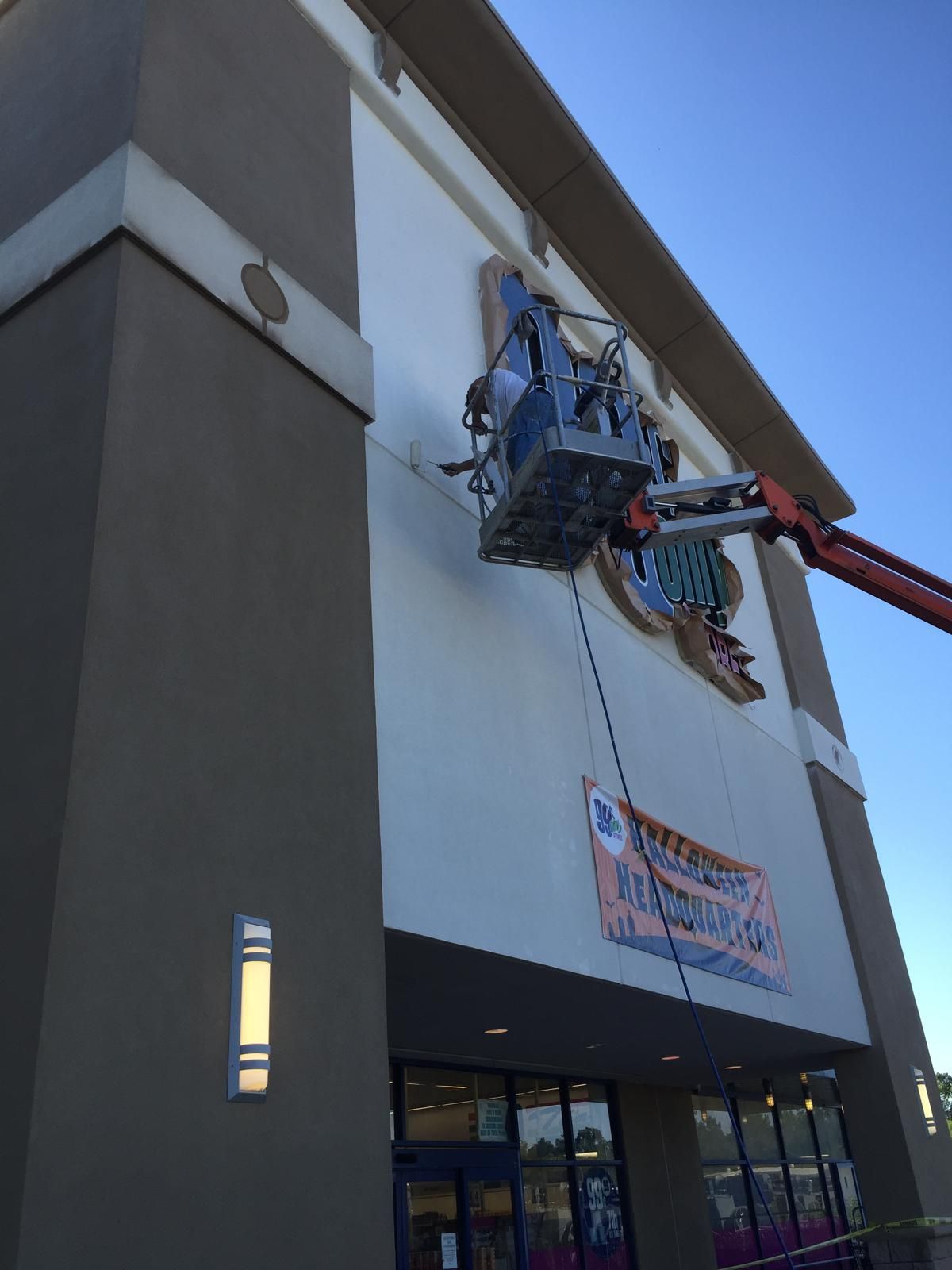 Workers in a lift repairing a building facade, with a promotional banner visible below.