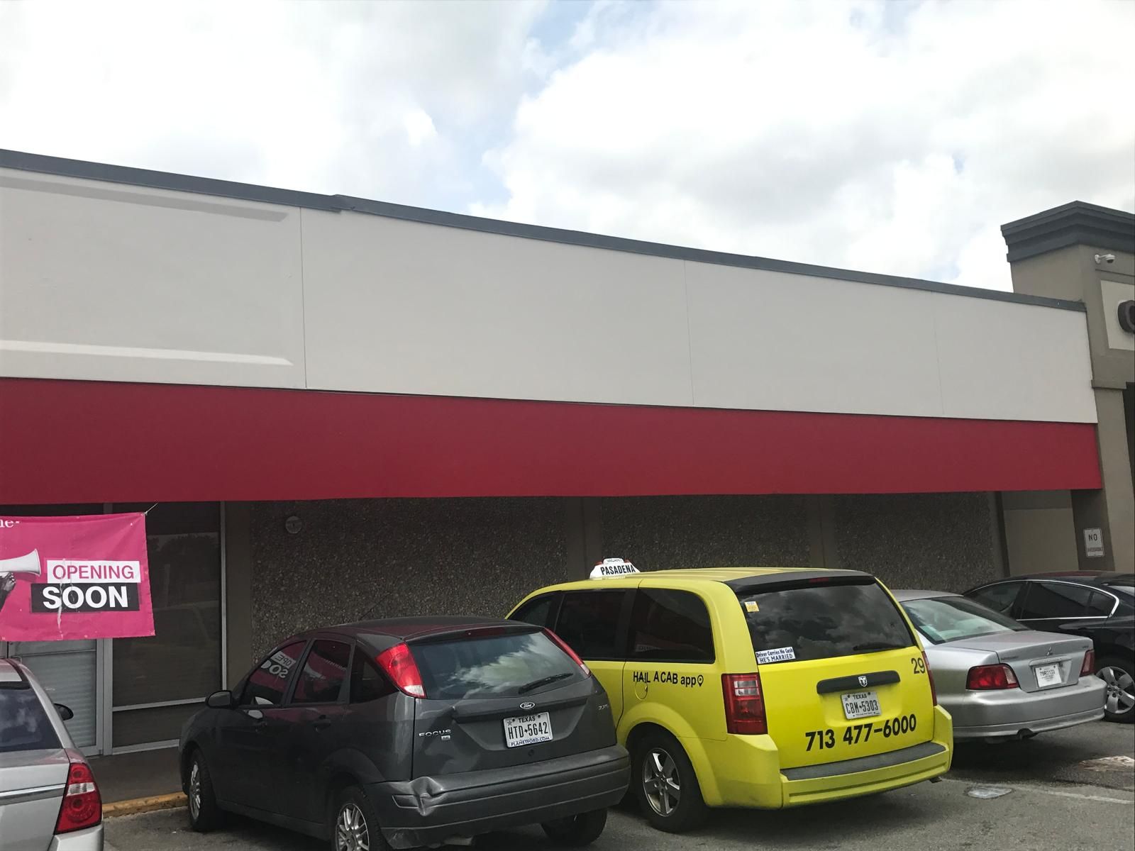 Exterior of a building with red awning and parked cars; 