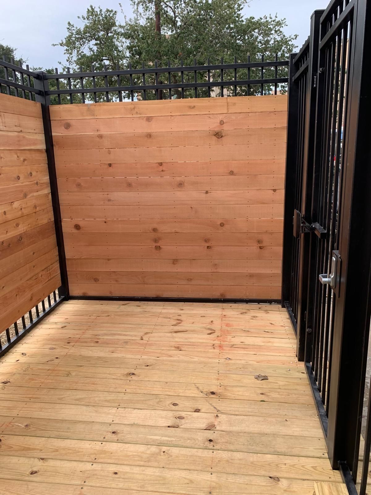 Wooden deck with wooden privacy walls and a black metal gate.
