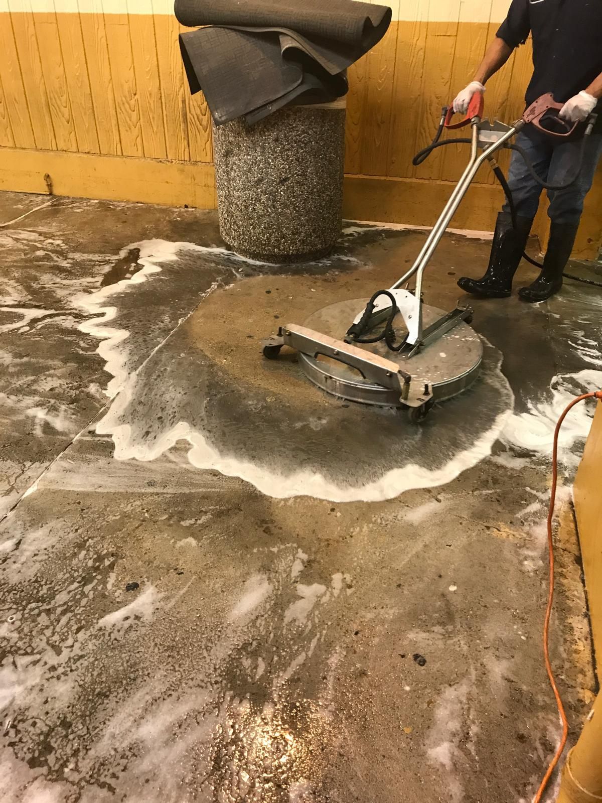 Person using a floor scrubber, creating foamy circles on a concrete floor.