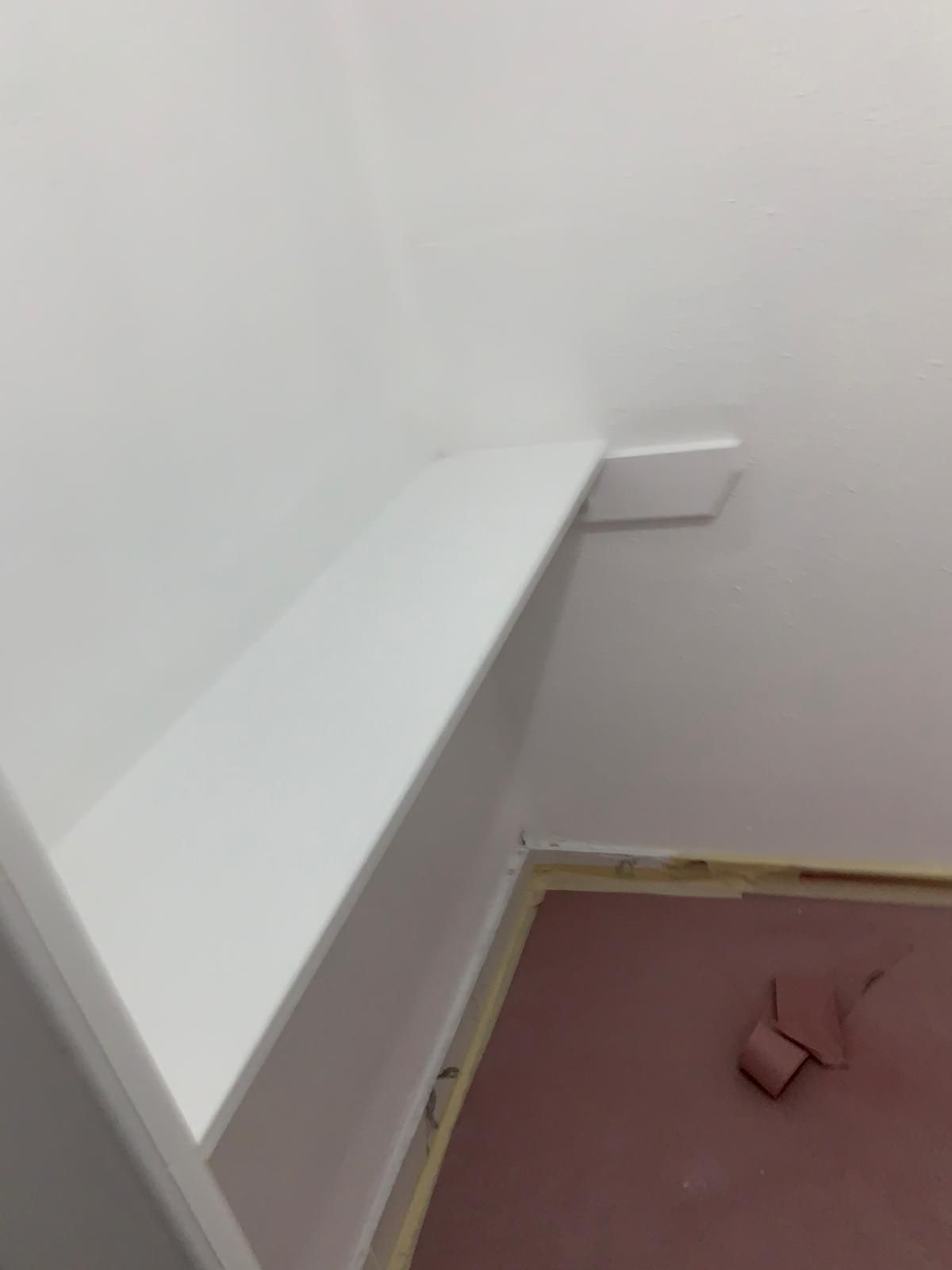 White painted wall corner with angled trim and flooring in progress.
