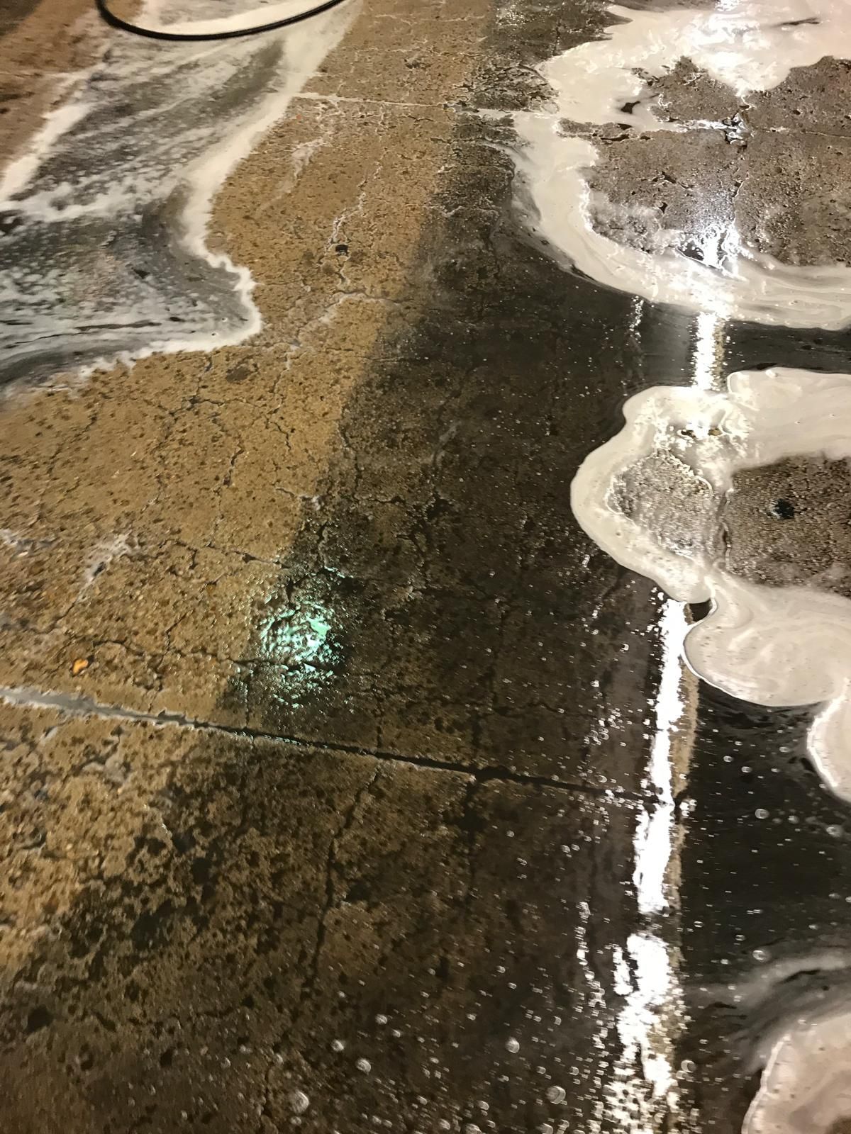 Concrete floor being cleaned with soap and water. The floor is dark and wet.