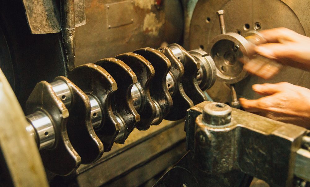 A Person Is Working On A Crankshaft On A Machine — Absolute Transmissions NQ In Hyde Park, QLD