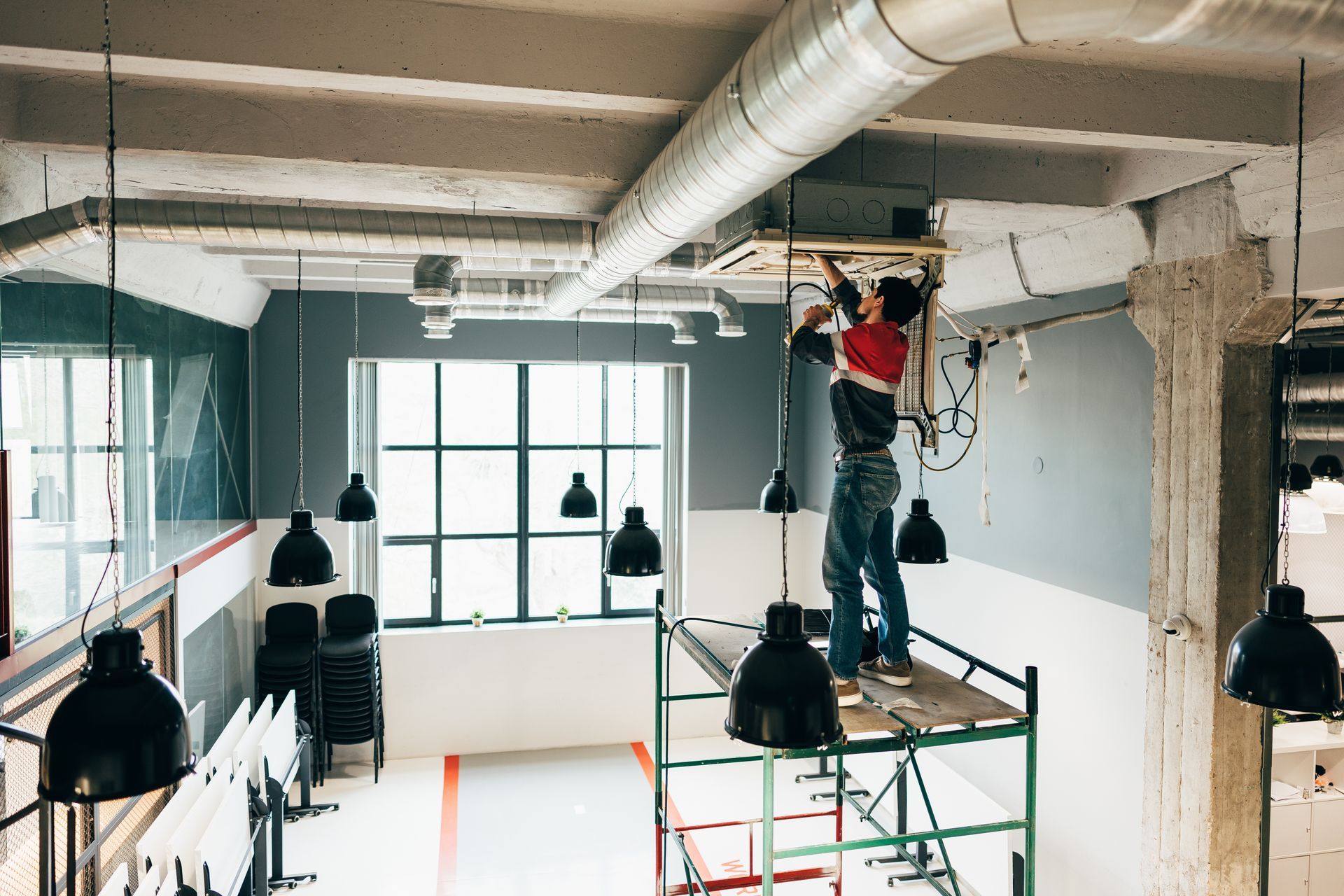 Worker on a scaffold installing equipment in the ceiling during a commercial build-out.
