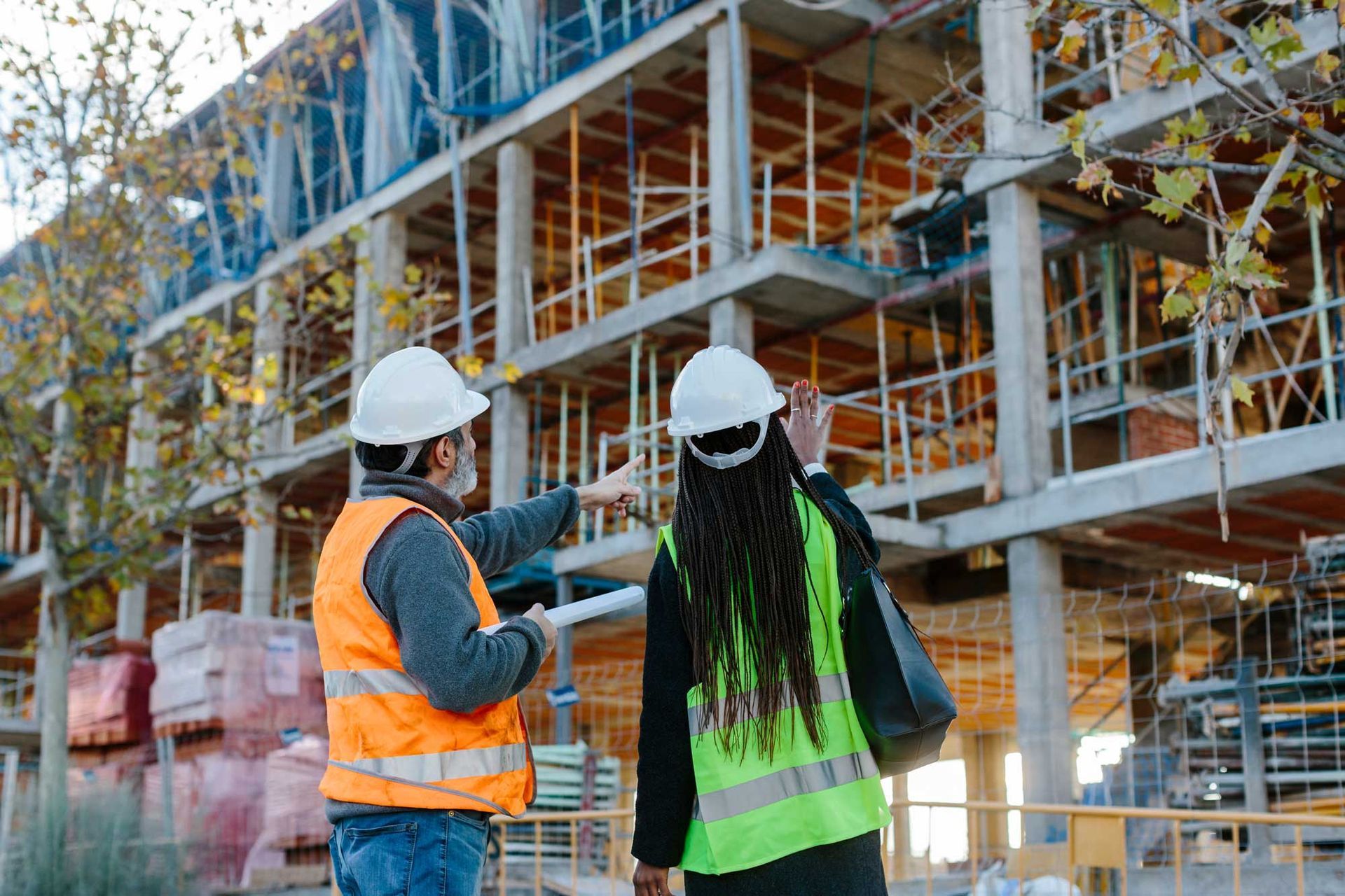 Woman engineer and male building contractor checking the development of a building in construction.