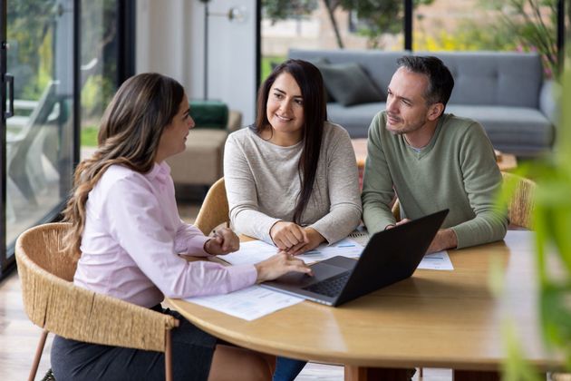 A man and a woman are sitting at a table with a laptop.