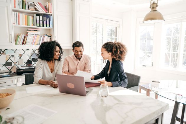 A woman is sitting at a table with a laptop and a man and woman.
