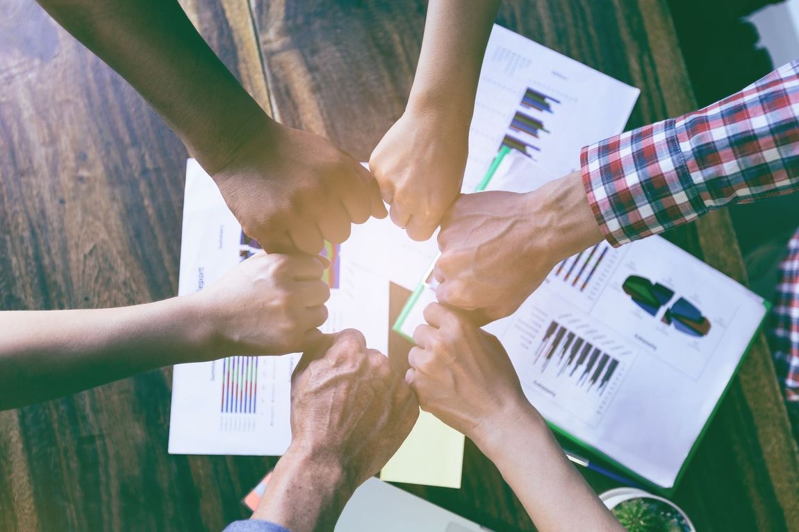 A group of people are putting their hands together in a circle.