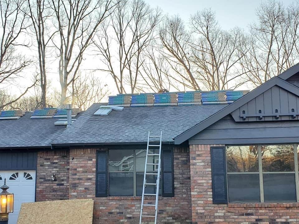 A ladder is sitting on the roof of a brick house.