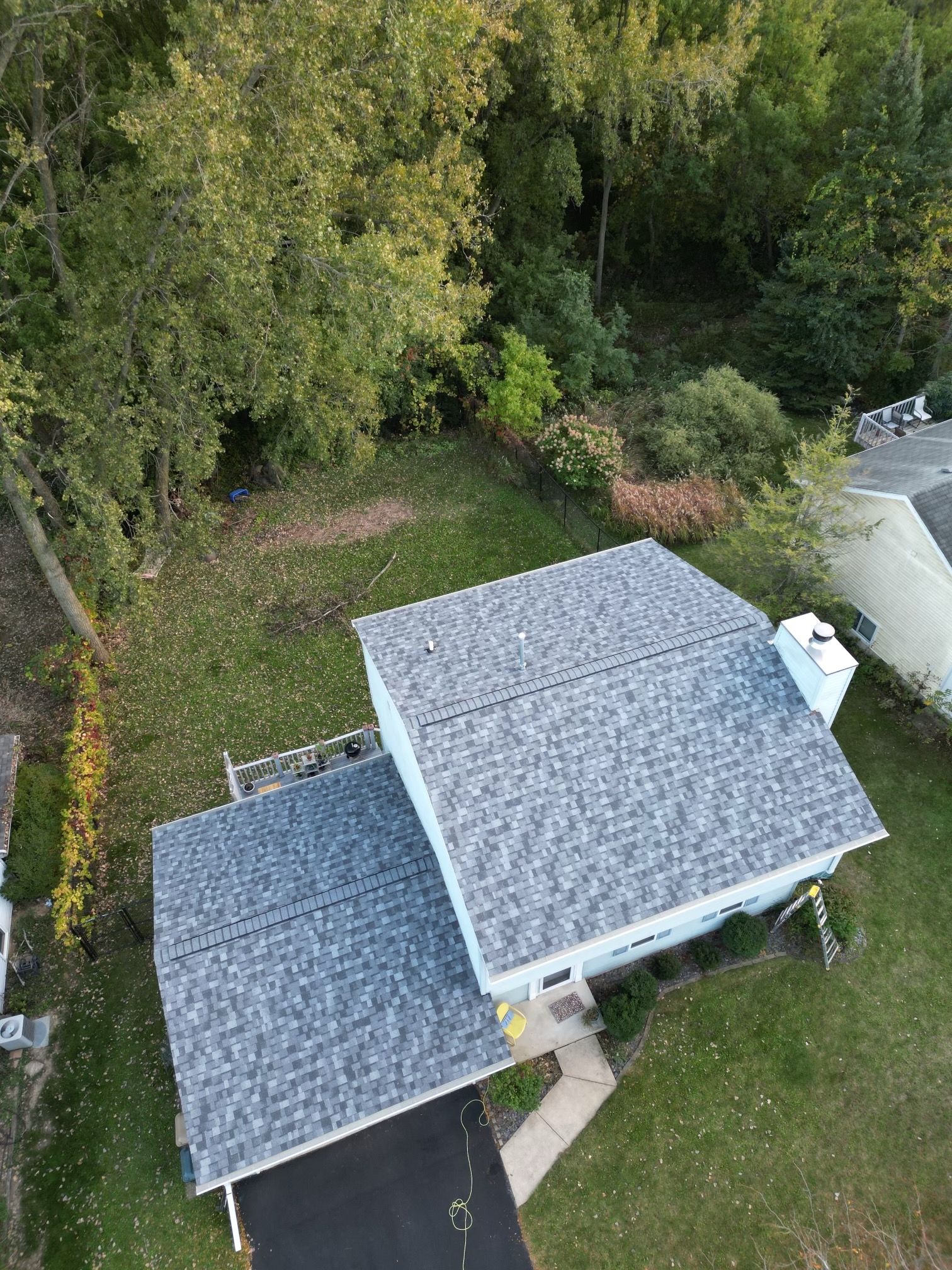 An aerial view of a house with a roof that is surrounded by trees.