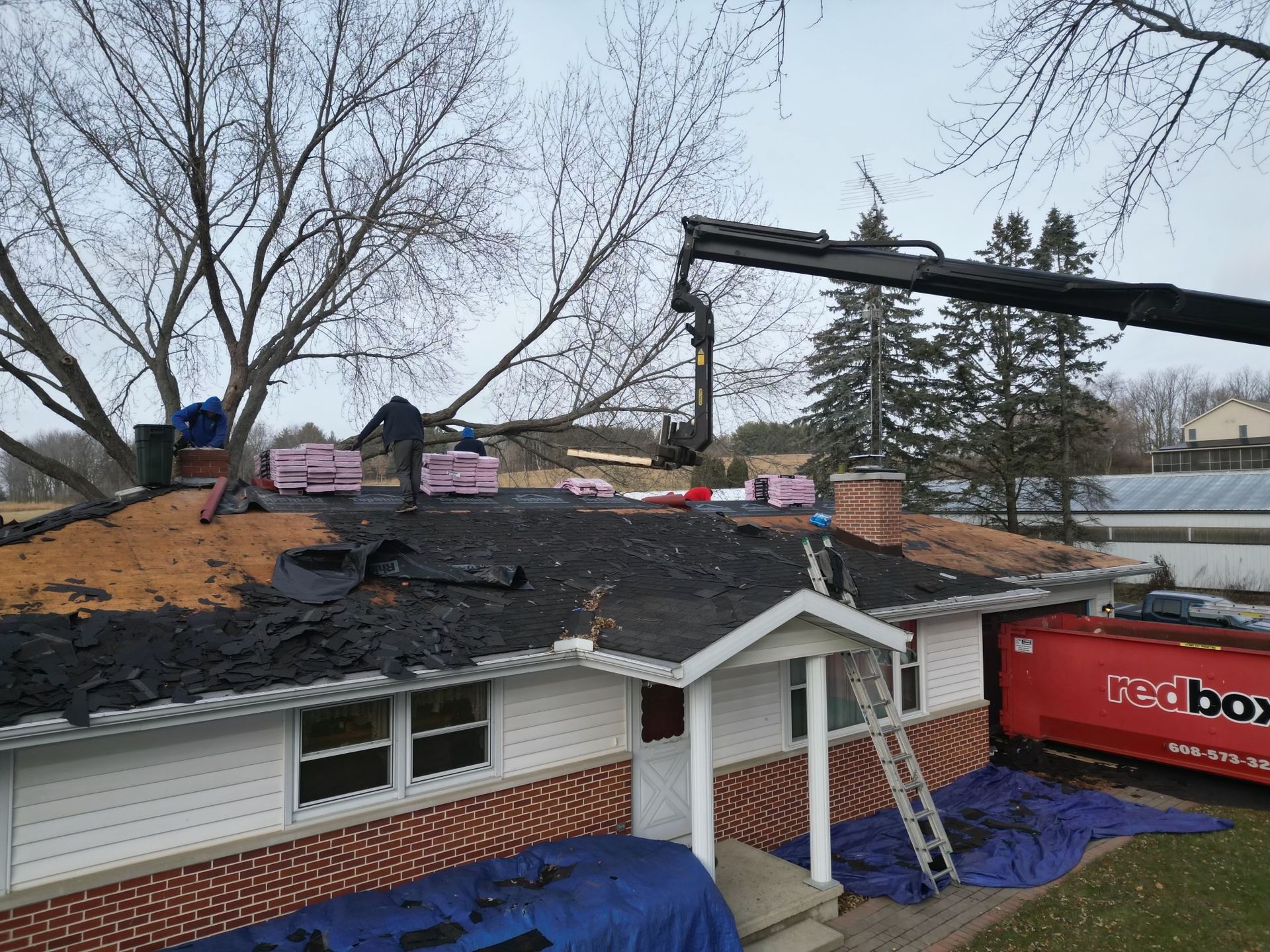 A crane is working on the roof of a house.