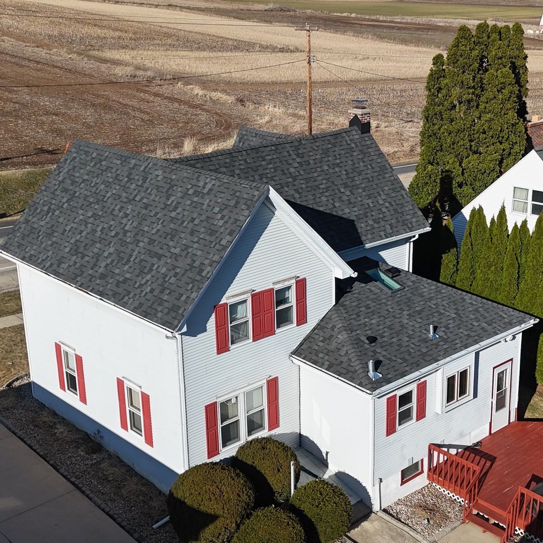 An aerial view of a white house with red shutters