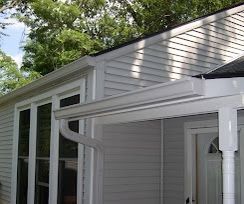 A white house with a porch and a white gutter.