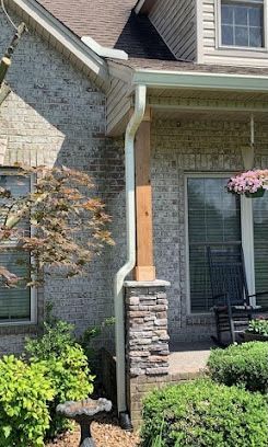 A brick house with a porch and a bird bath in front of it.