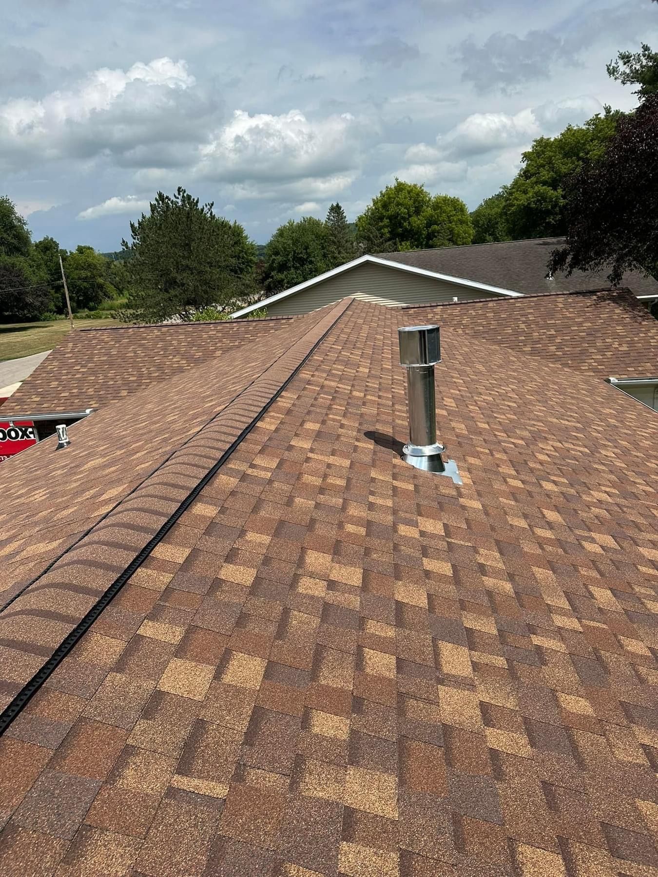 A roof with a chimney on top of it and trees in the background.