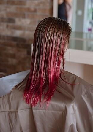 Una lampada a sospensione in rame riflette l'interno di una stanza. Sullo sfondo, un soffitto a cassettoni decorato.