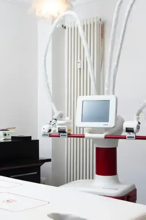 Dispositivo medico con monitor e bracci articolati in una stanza bianca.